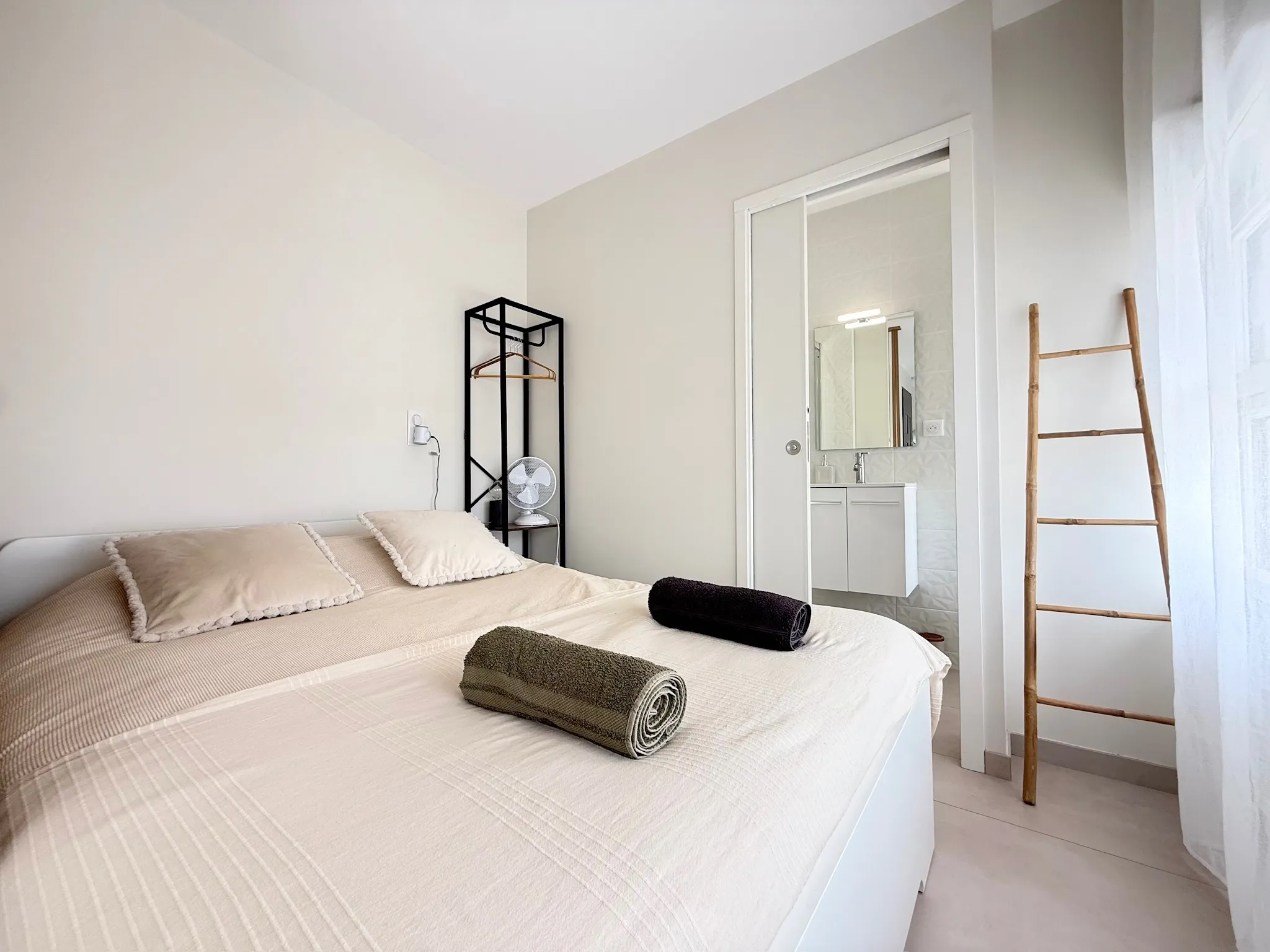 Chambre aux murs clairs avec porte coulissante donnant sur une salle d'eau carrelée de blanc