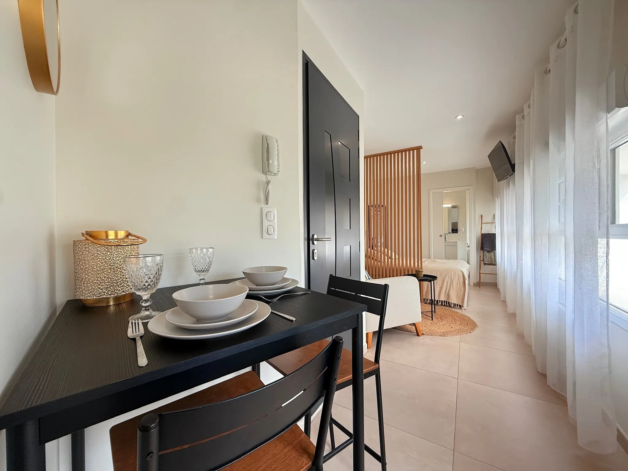 Table haute noire dressée pour deux, avec vue sur le studio, le coin chambre et la cloison à lames de bois