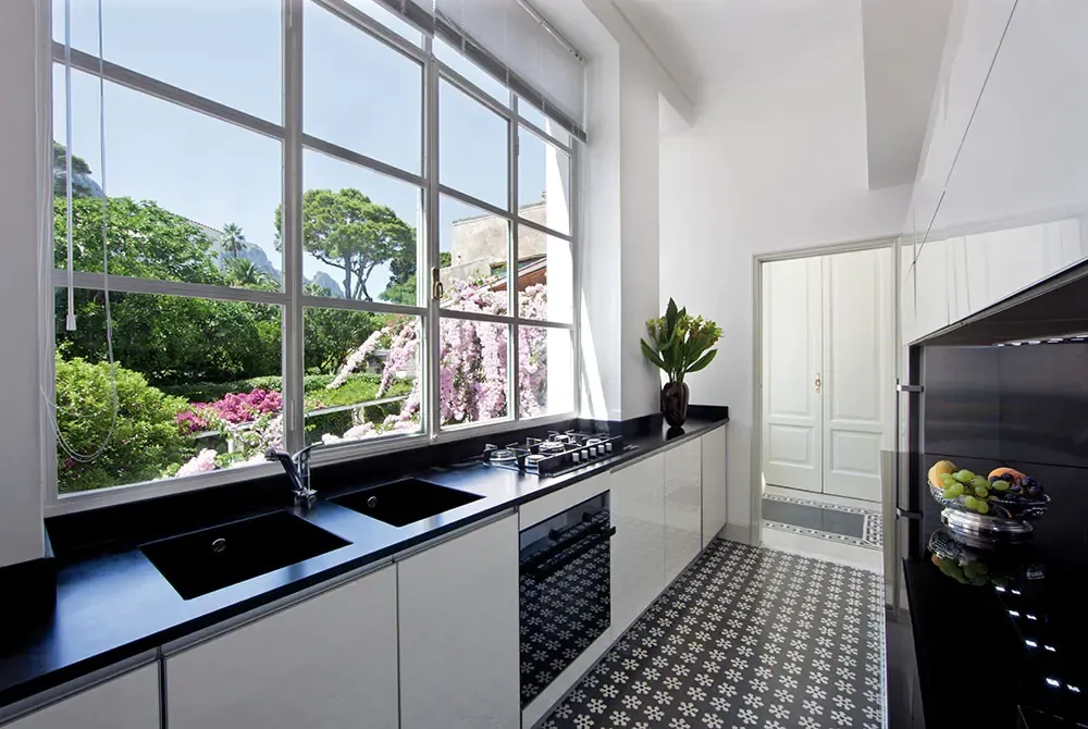 Cuisine claire avec une grande fenêtre à carreaux ouvrant sur un jardin