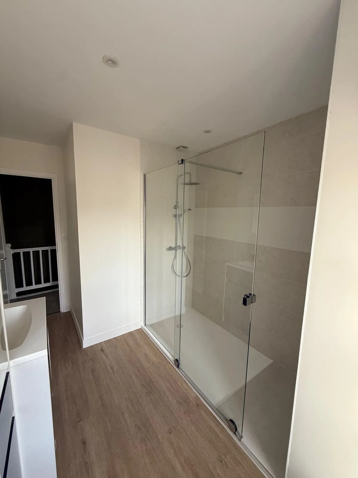 Douche à l'italienne avec colonne de douche, receveur blanc extra-plat et paroi en verre