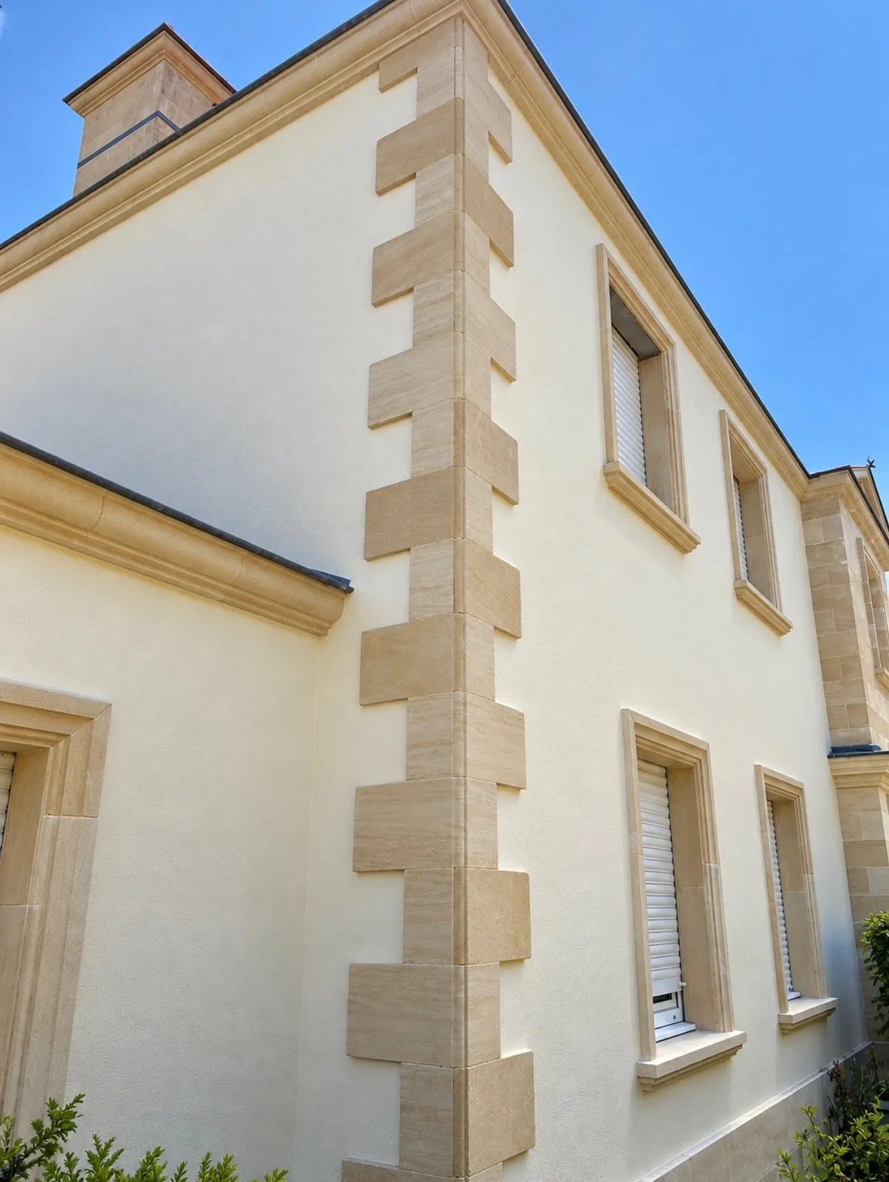 Angle de façade enduite avec chaînage et encadrements de fenêtres en pierre claire